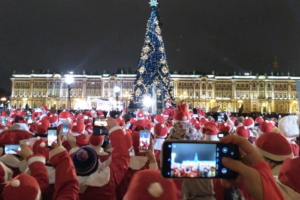 Десятки петербуржцев в костюмах Дедов Морозов пробежали по Дворцовой площади, а на главной елке зажгли огни. Вот как это было