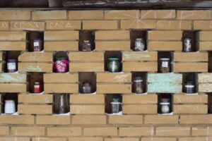 Баночки с «довоенной водой» и «счастьем». Это арт-проект петербурженки в стене гаража на площади Мужества